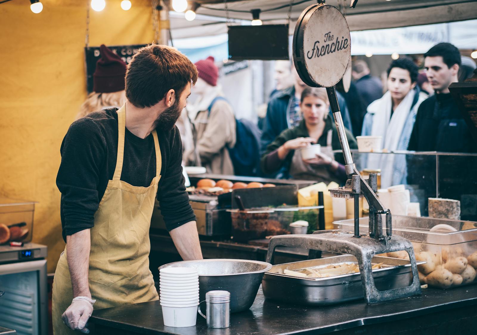 Dynamic scene of a street food vendor working in a busy market, engaging with diverse customers.
